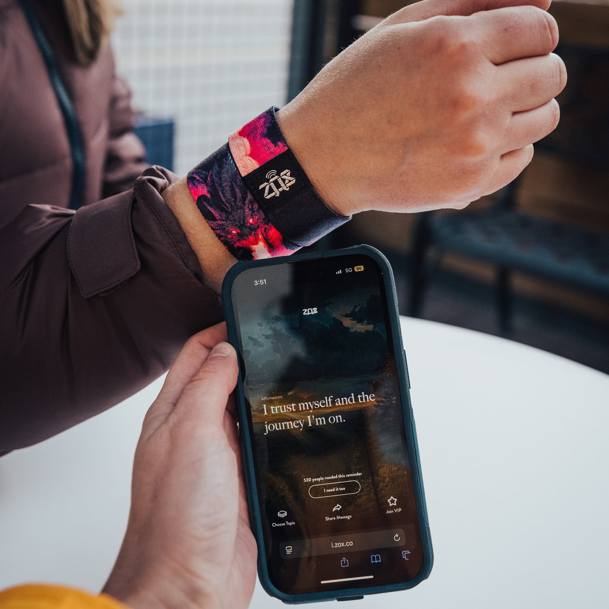 Person using a smartphone with a watch displaying a colorful band.