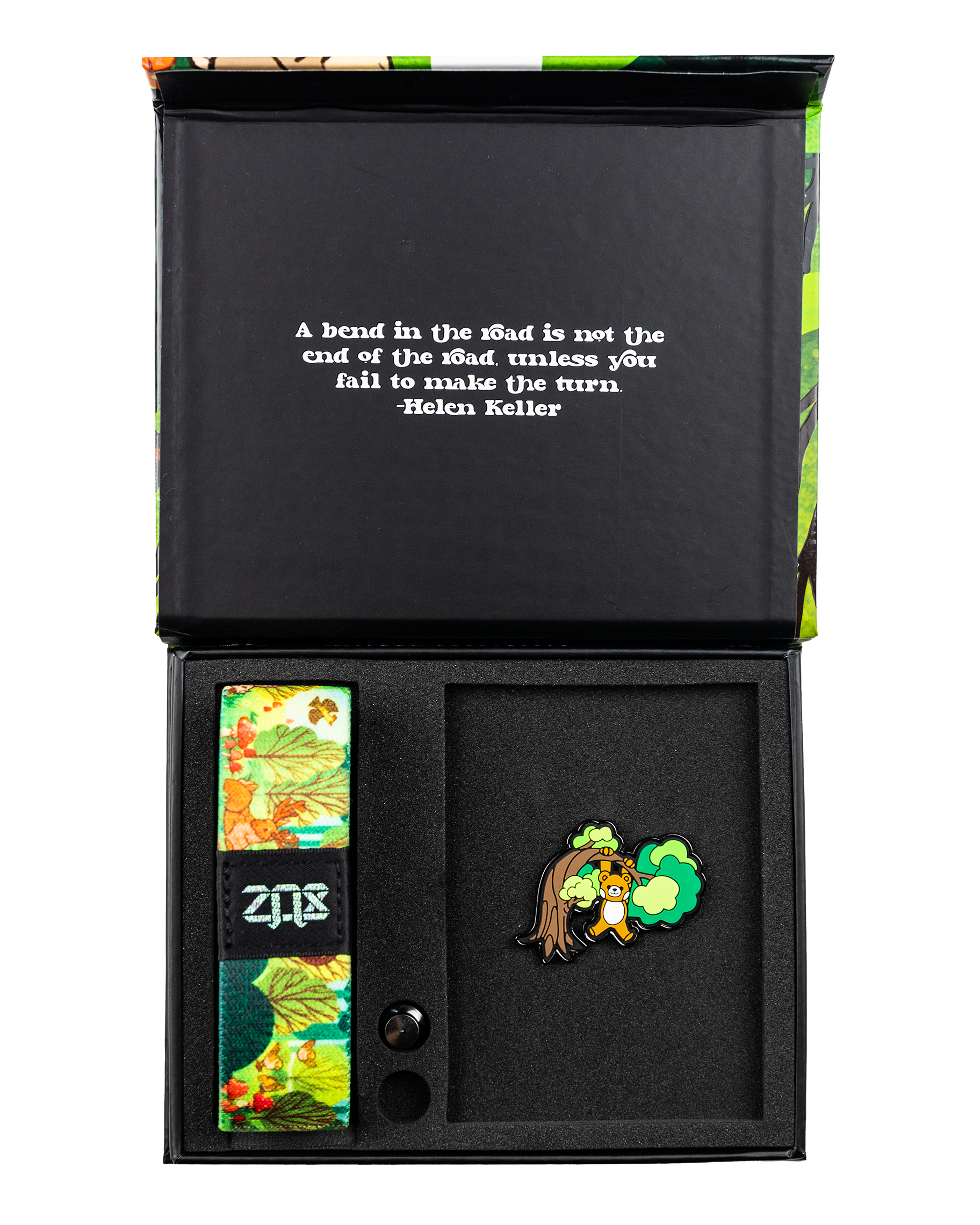 This is a reversible strap. The outside design is a cartoon scene of a bear climbing a tree in the jungle. It comes with a matching lapel pin of the bear hanging on a limb, and a collector's box. 