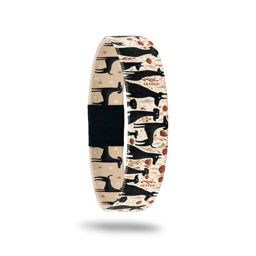 Certified Dog Person bracelet showing black dog silhouettes among warm-toned flowers on cream