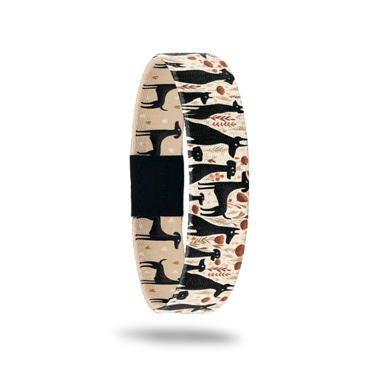 Certified Dog Person bracelet showing black dog silhouettes among warm-toned flowers on cream