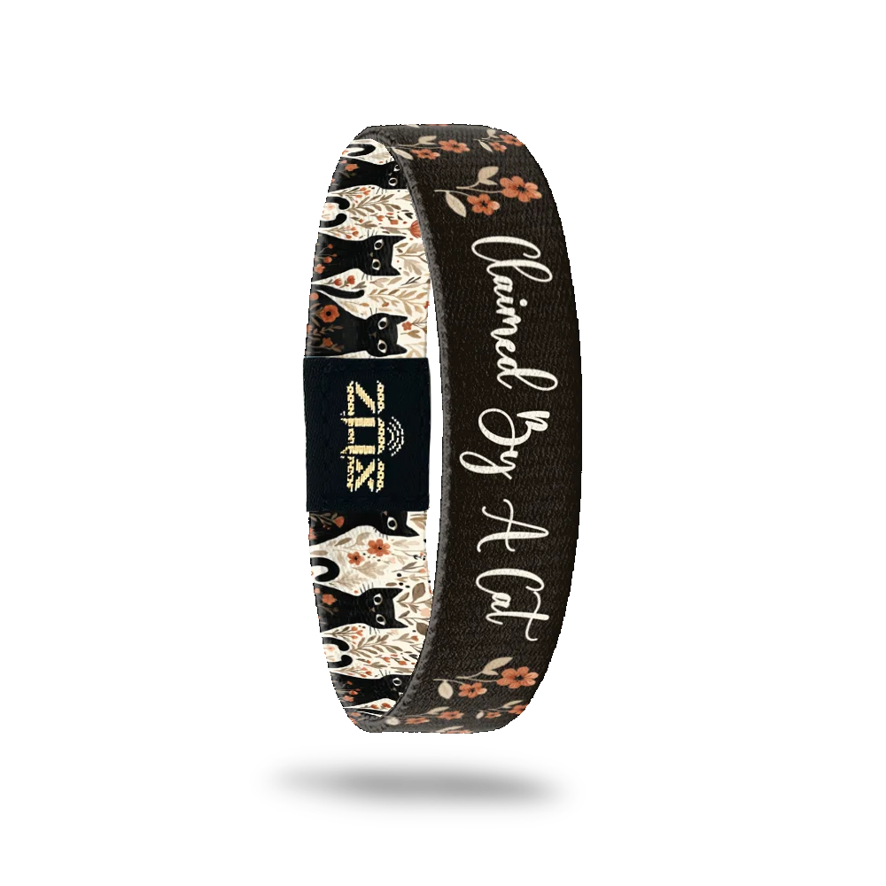 Inside of the Claimed By A Cat bracelet, with the words Claimed By A Cat across the cat and floral print
