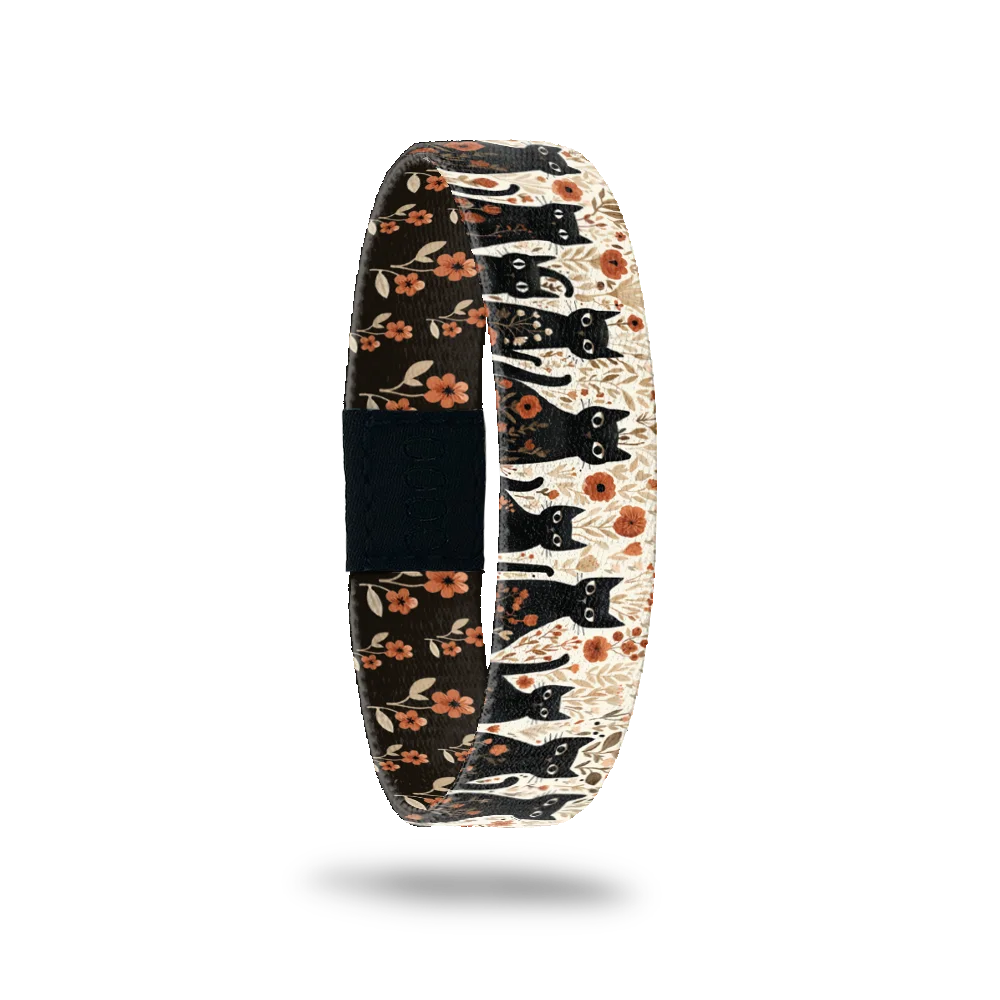 Claimed By A Cat bracelet showing black cats among orange flowers on a warm cream ground