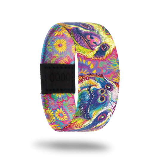 A vibrant bracelet featuring colorful, psychedelic illustrations of smiling sloths surrounded by multicolored floral patterns. The background is a mix of pink, purple, blue, and yellow hues. A black rectangular patch with etched serial numbers is visible on one side of the strap.