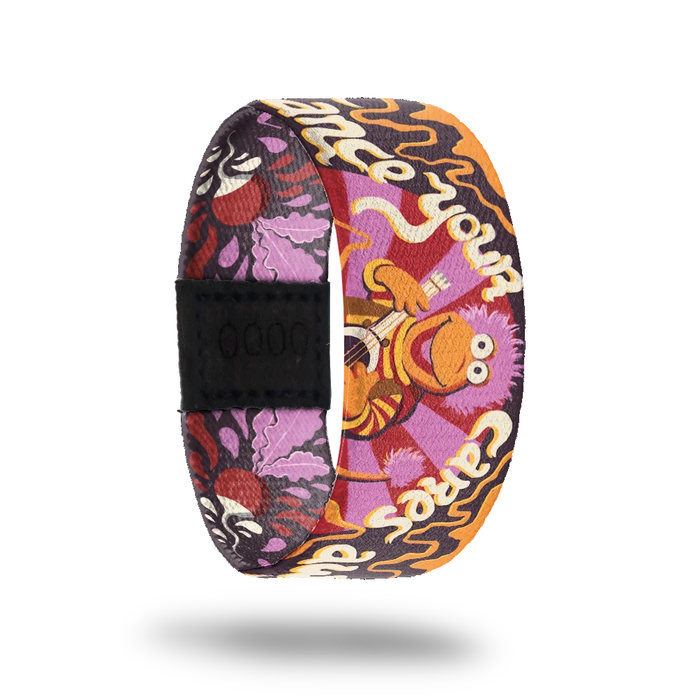 A colorful bracelet featuring Gobo from Fraggle Rock, depicted playing a guitar against a vibrant background with purple, orange, and red swirls. The phrase "Embrace your cares away" appears in playful white font. The design includes floral and abstract elements