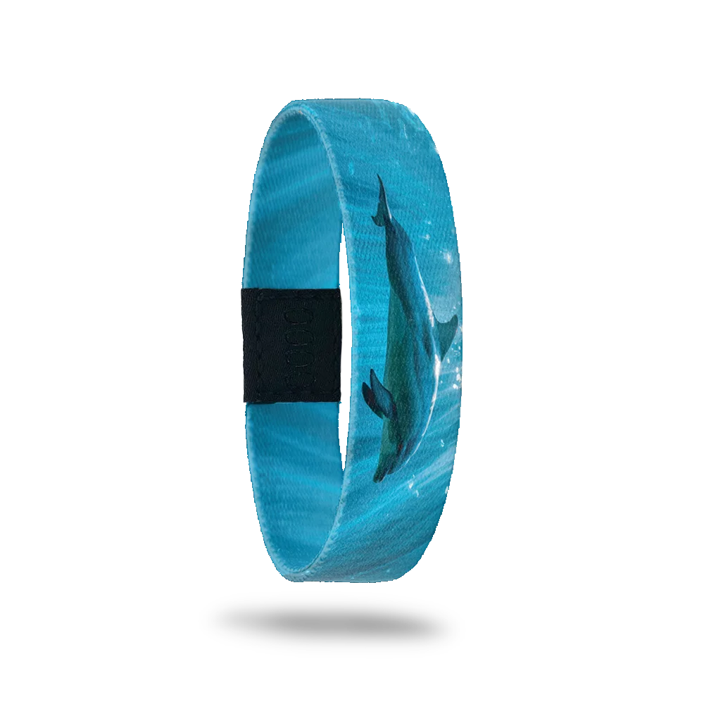 Product photo of the outside of the Free Spirit bracelet, featuring a serene underwater scene with a dolphin swimming gracefully through blue waters. The background includes light reflections on the water, creating a peaceful, aquatic vibe. A black rectangular patch with etched serial numbers is visible on one side of the strap.