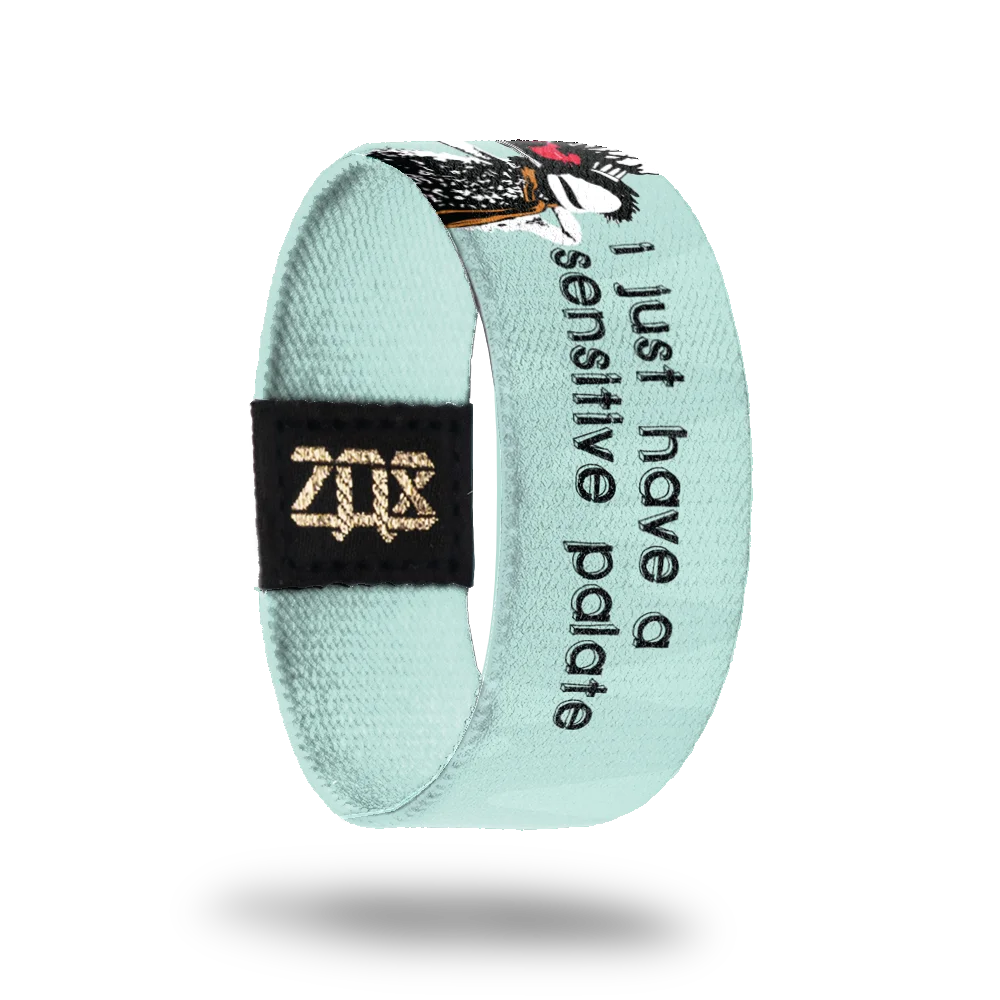 A pastel blue bracelet for #1-100 featuring Boober from Fraggle Rock alongside the phrase, "I just have a sensitive palate" in black text. Boober, wearing his signature hat, is depicted with a serving platter of beets.