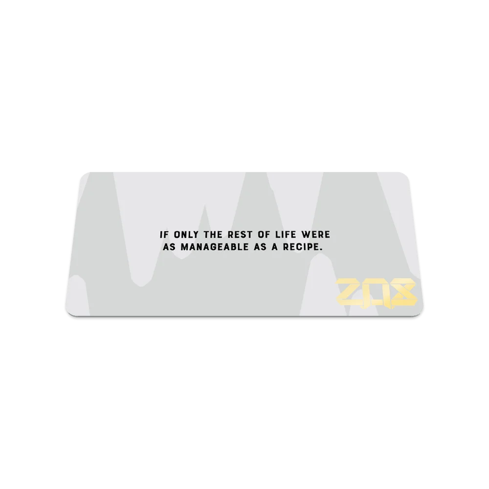 A rectangular bracelet display card with a white background and subtle abstract shapes. The text reads, "If only the rest of life were as manageable as a recipe," in black font, centered on the card. The ZOX logo is featured in bold gold lettering in the lower right corner.