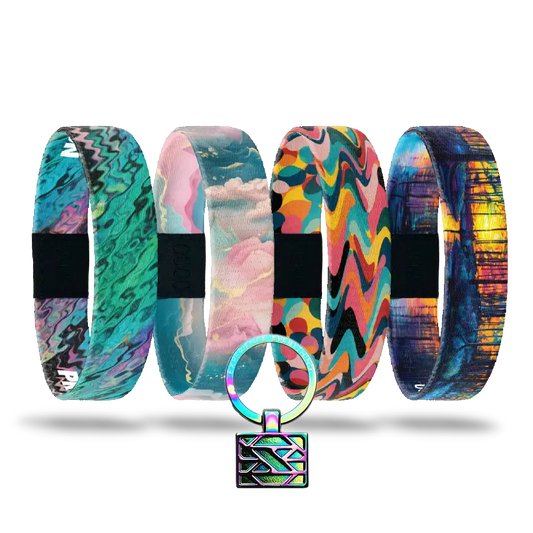 The Self-Care Pack features five vibrant, patterned affirmation bracelets with unique abstract designs, arranged in a row. A small round keychain with a geometric print and metallic lock completes this inspiring set.