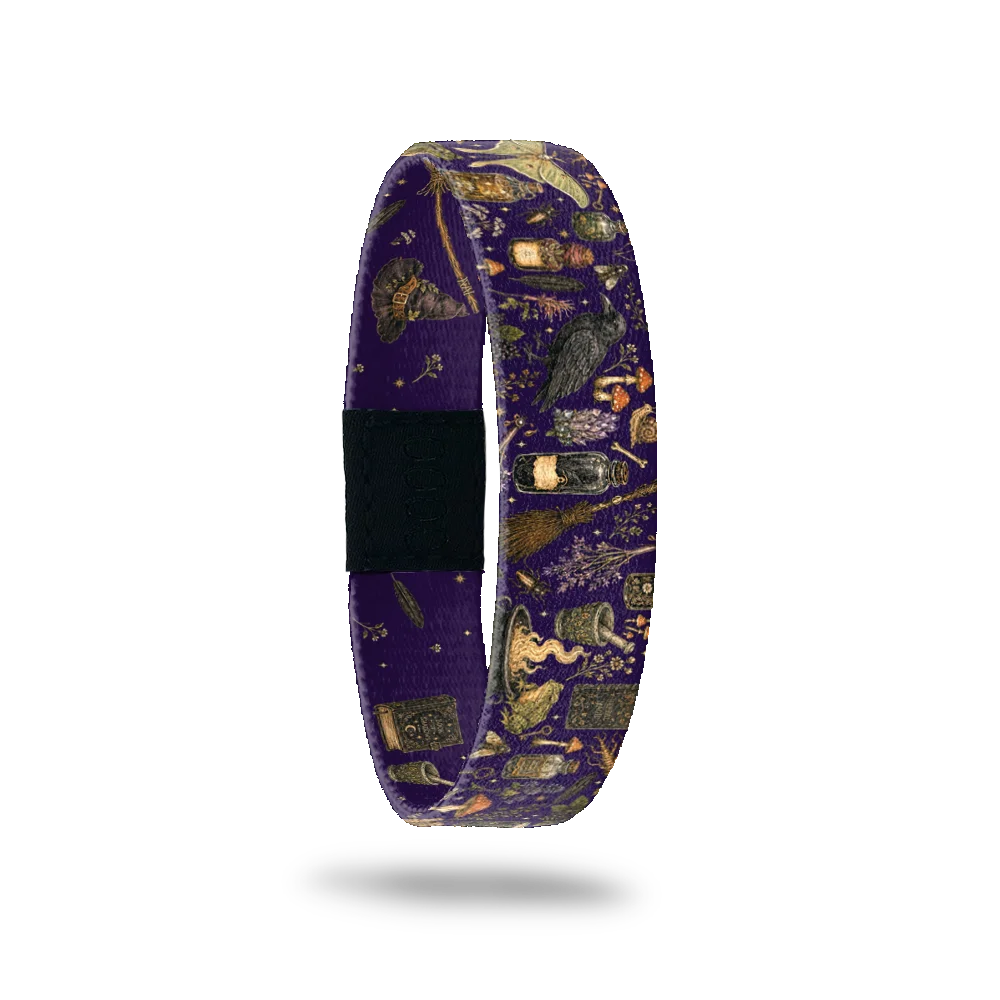 Magic In My Hands bracelet showing potion bottles, spell books, a raven and a broom on deep purple