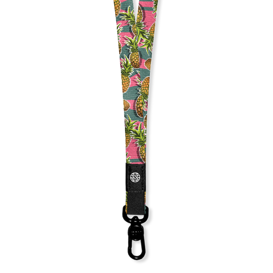 A lanyard with a green and pink horitzontal straip design. On top of the lines are pineapples all over and the inside reads Ohana. The lanyard has a metal pull-down clip but comes with two extra attachments to create a breakaway version too.