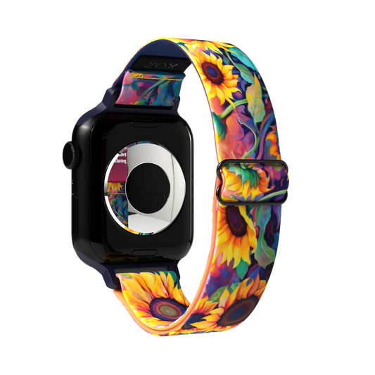 Product photo of the outside of the Radiate Positivity watch band. The design is vibrant and features a colorful sunflower pattern with bright yellow, orange, and green hues against a deep, dark background. The sunflowers are detailed with various shades, creating a realistic and lively appearance. The strap has a black buckle and loops to secure the watch in place.