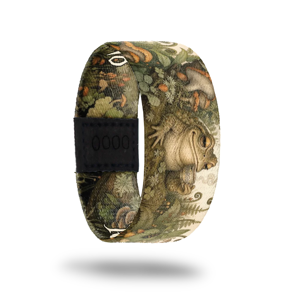 Respectfully, No bracelet showing a toad holding a teacup in a mossy woodland of ferns and mushrooms