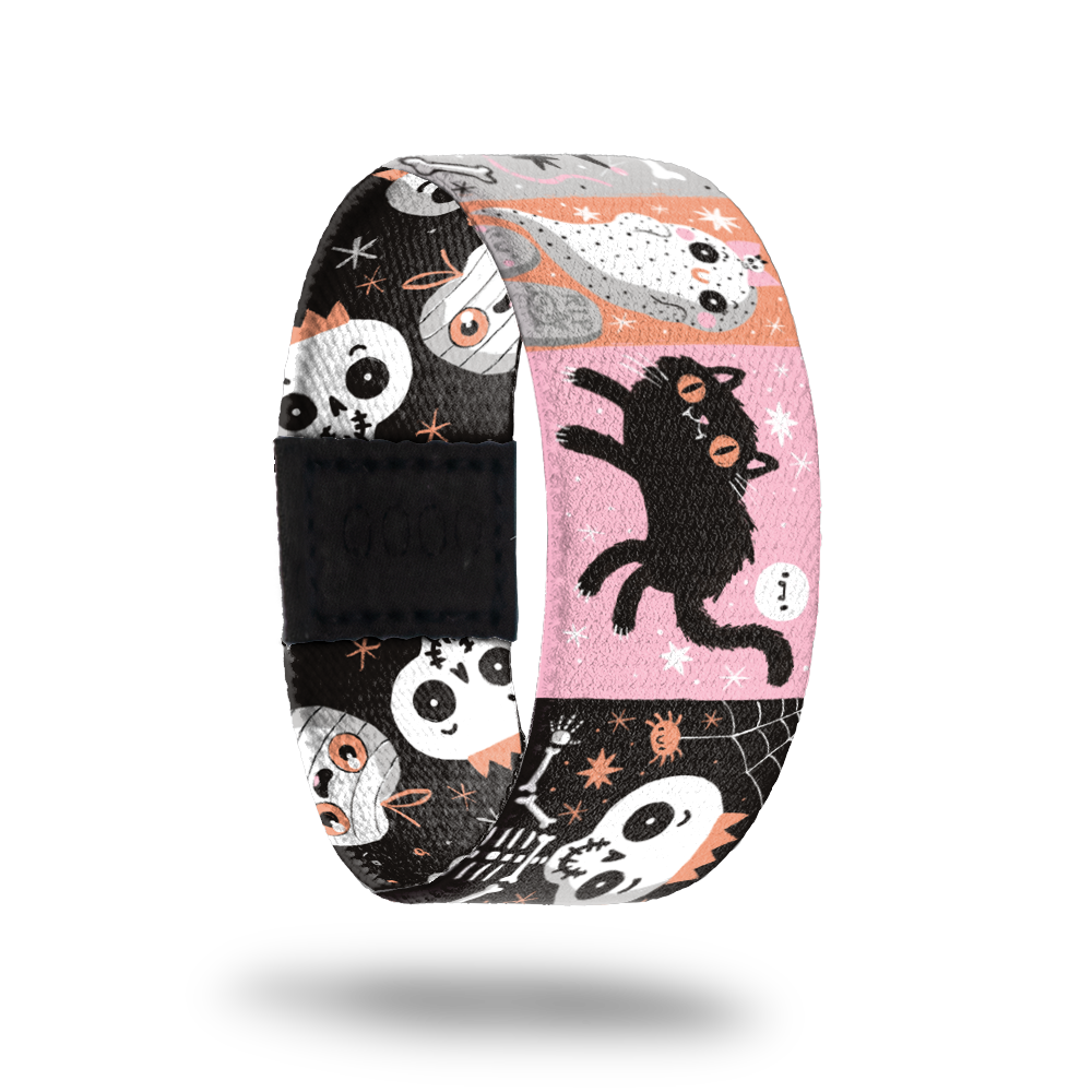 A patchwork design with various cartoon characters. Pink, orange, white and black are the main colors with ghosts, black cats, skeletons etc. Inside is black with white skeletons and ghosts with smiley faces and says Creepin' It Real. 