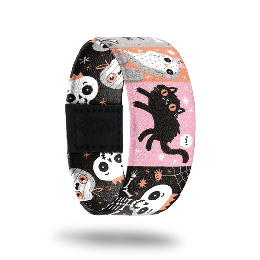 A patchwork design with various cartoon characters. Pink, orange, white and black are the main colors with ghosts, black cats, skeletons etc. Inside is black with white skeletons and ghosts with smiley faces and says Creepin' It Real. 