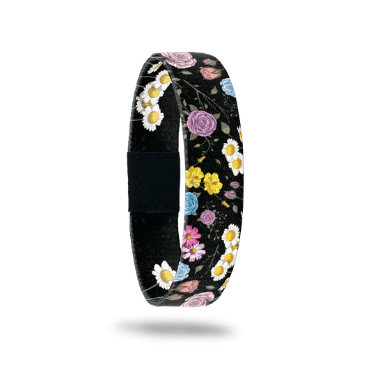 Wristband single that has a black base. The design is all different kinds and colorss of flowers. The inside is the same and says In A Field Of Roses...