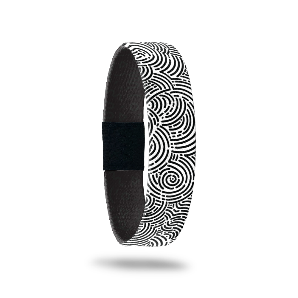 Wristband single with a black and white circular maze design all over. The inside is the same and in teal reads One Day At A Time.