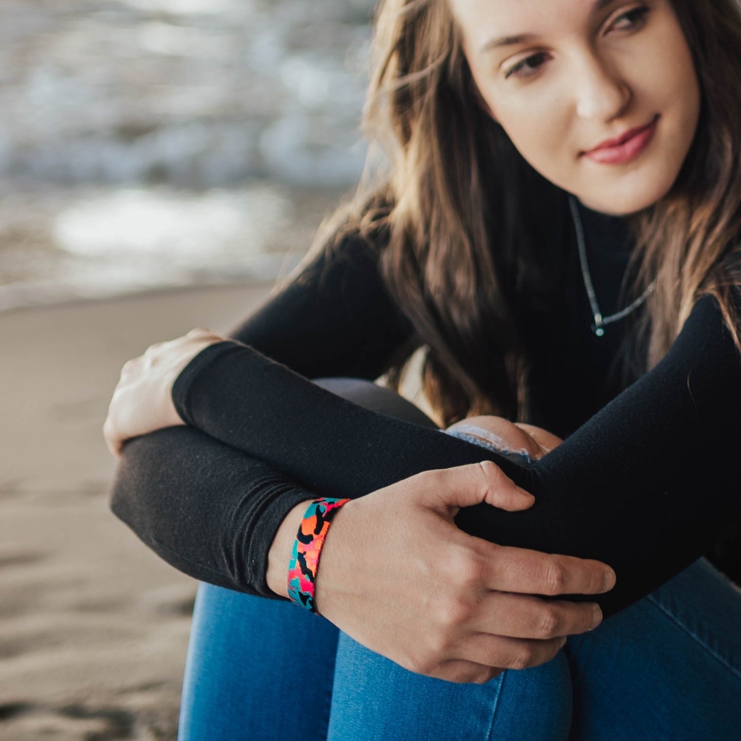 Lifestyle image close up of someone's arms crossed in front of their knees with Fearless on their wrist 