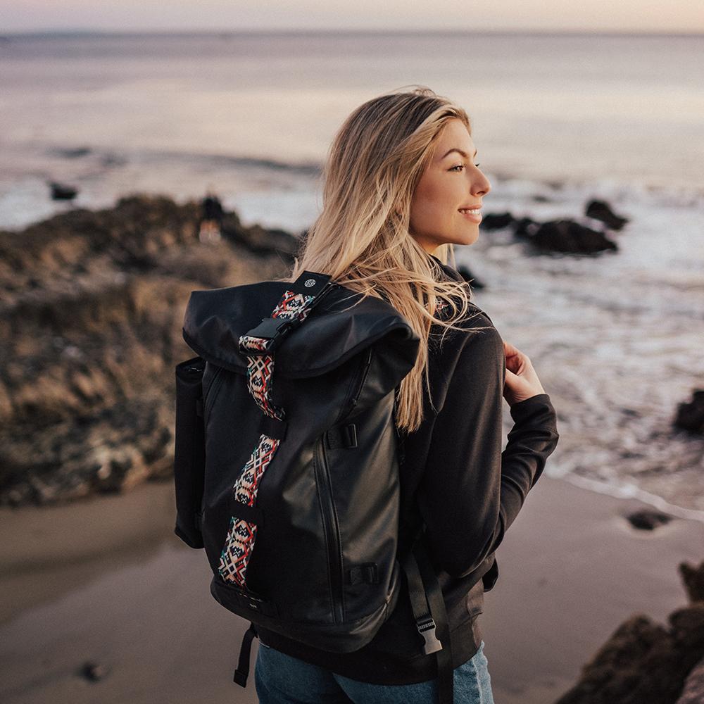 lifestyle photo of the Imperial v2 with a different colored closure strap on a woman's shoulders while at the beach 