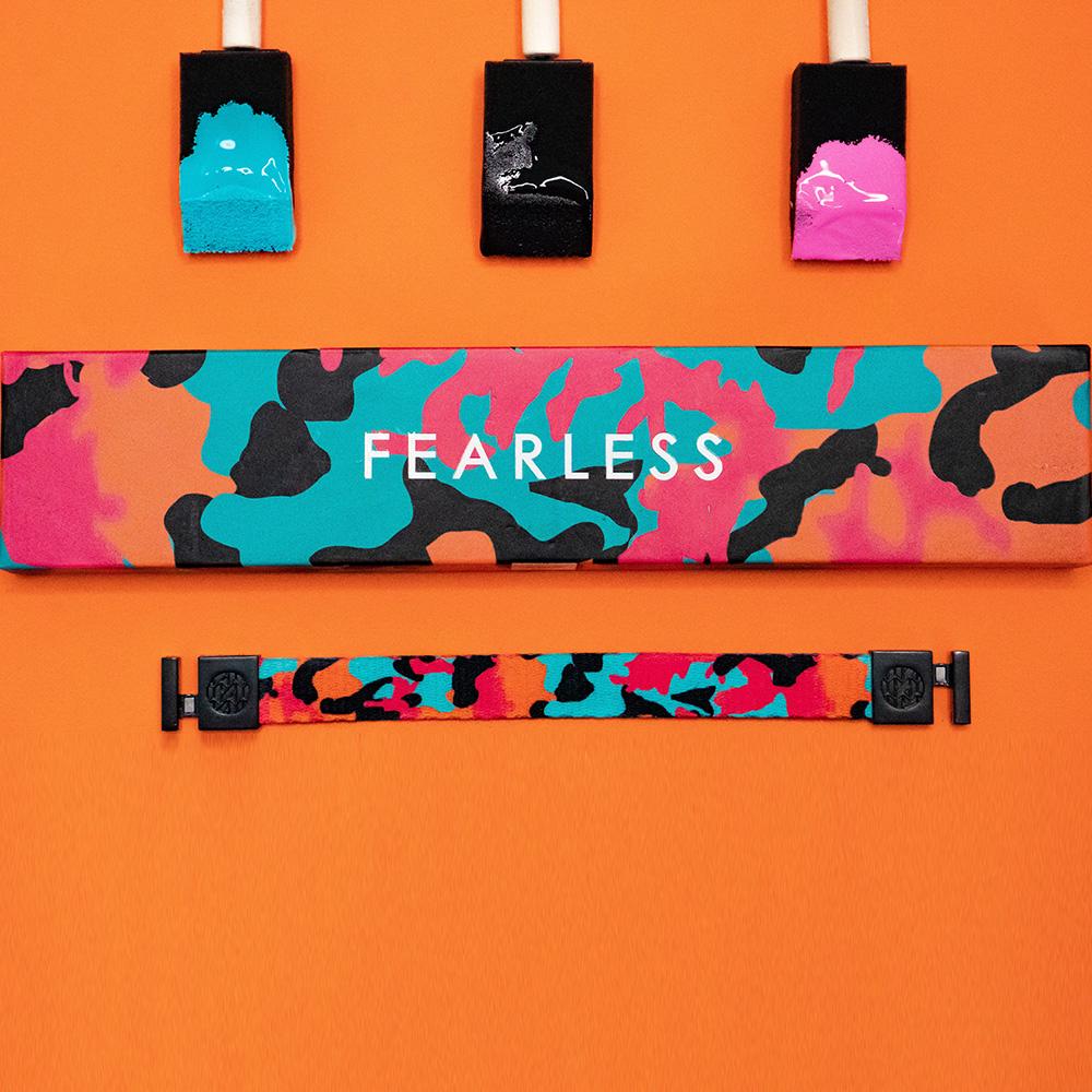 Studio image of Fearless and the box it comes in next to three paint brushes 